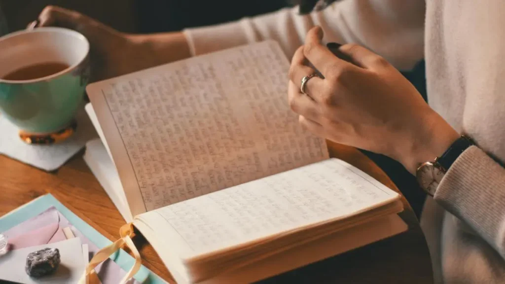 Caderno aberto com escrita à mão ao lado de uma xícara de chá, em ambiente aconchegante com luz quente e suave.