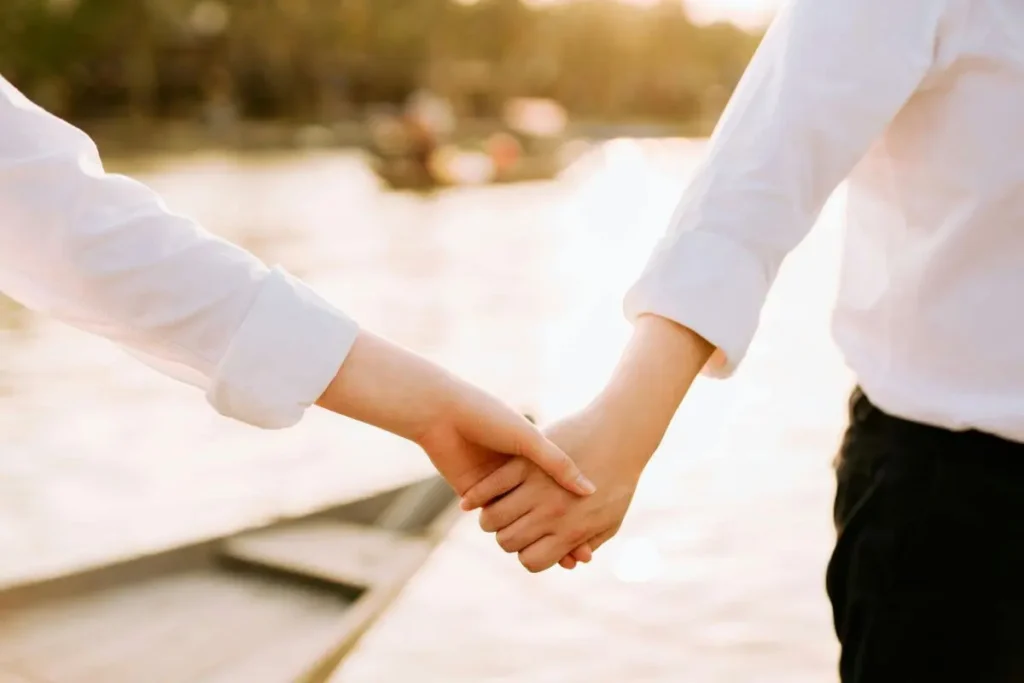 Casal de mãos dadas em momento de reconexão, com luz quente e suave, transmitindo cuidado, presença genuína e apoio emocional.