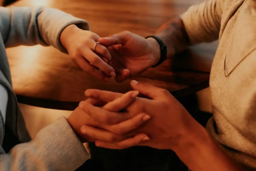 Casal de mãos dadas em ambiente acolhedor, transmitindo presença, reconexão emocional e apoio mútuo.