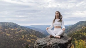 Mulher meditando em posição de lótus na natureza com olhos fechados