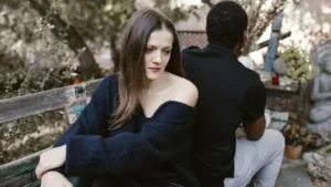 Casal sentado lado a lado em banco ao ar livre olhando em direções diferentes representando distância emocional no relacionamento
