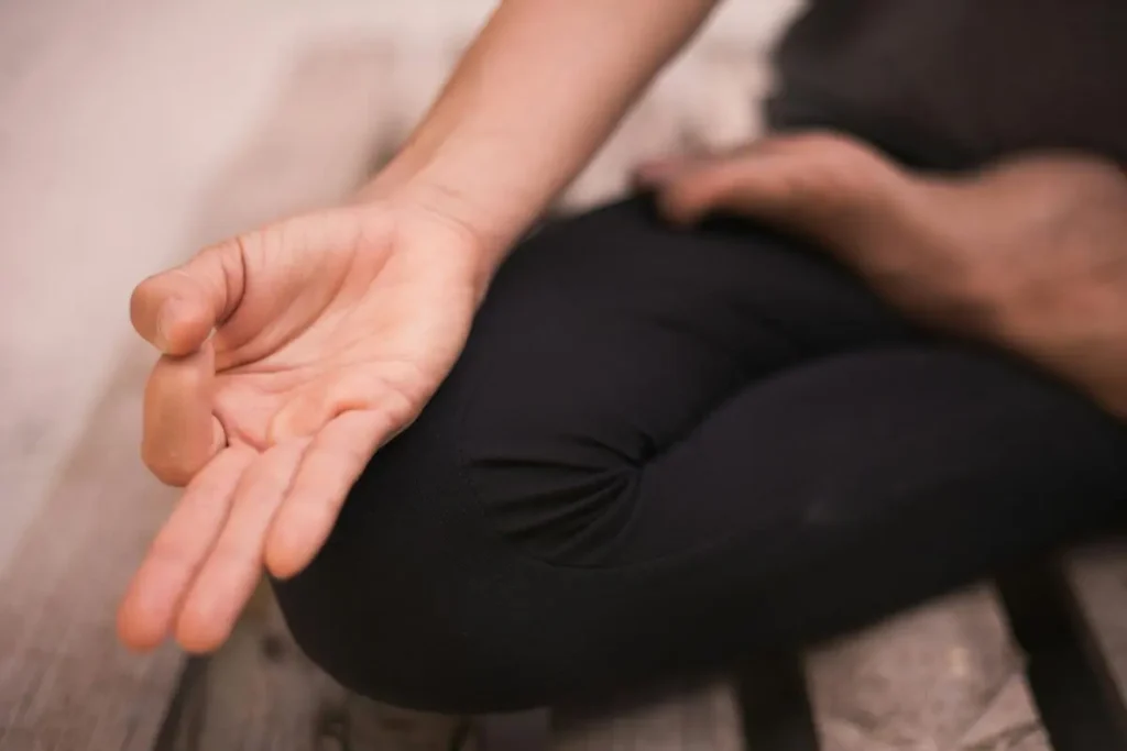 Mãos abertas apoiadas sobre os joelhos em postura relaxada, representando calma, presença e tranquilidade.