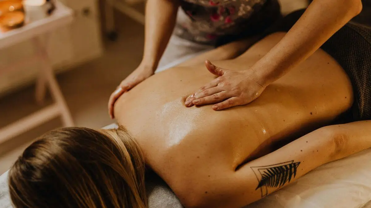 Pessoa recebendo massagem relaxante nas costas em ambiente acolhedor, com luz quente e sensação de cuidado e bem-estar.