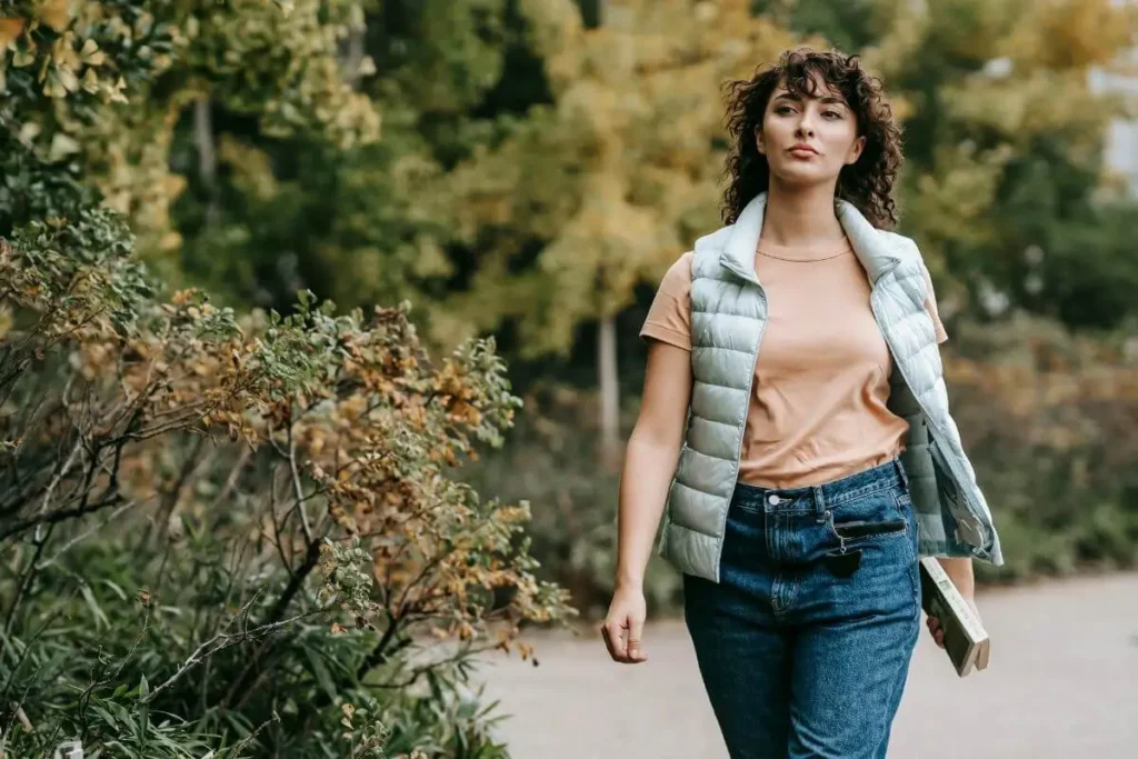 Mulher caminhando ao ar livre com expressão determinada e leve, transmitindo sensação de recomeço, liberdade emocional e confiança.
