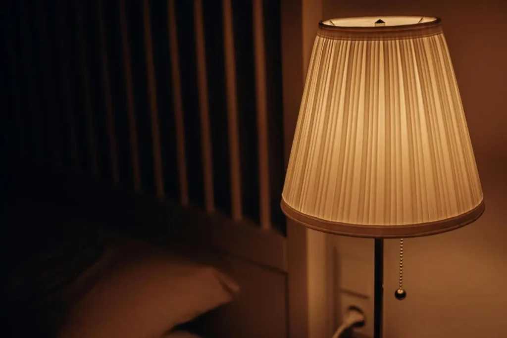 Abajur com luz quente e suave em quarto escuro criando ambiente aconchegante e tranquilo para dormir melhor