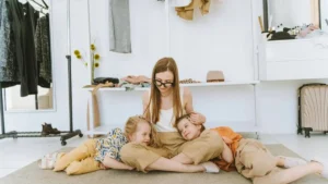 Mãe sentada no chão com dois filhos pequenos recostados nela em momento de conexão e presença consciente