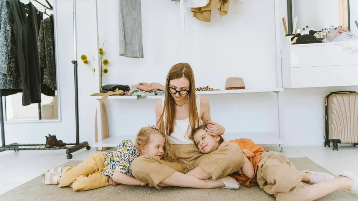 Mãe sentada no chão com dois filhos pequenos recostados nela em momento de conexão e presença consciente