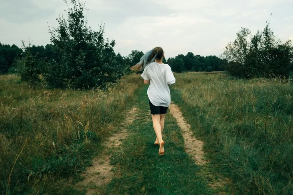 Pessoa caminhando descalça em trilha na natureza representando meditação em movimento e presença consciente