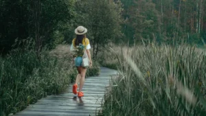 Mulher caminhando em trilha de madeira cercada de natureza verde representando meditação em movimento para quem não consegue ficar parado