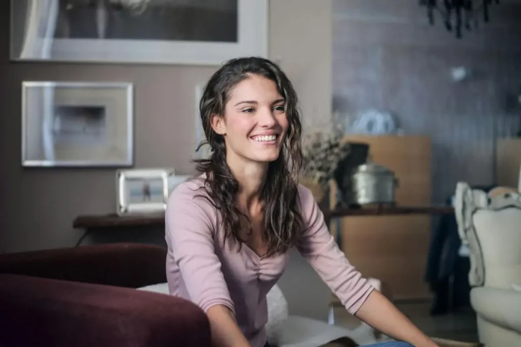 Mulher sorrindo com expressão leve e genuína em ambiente doméstico acolhedor transmitindo leveza emocional e bem-estar