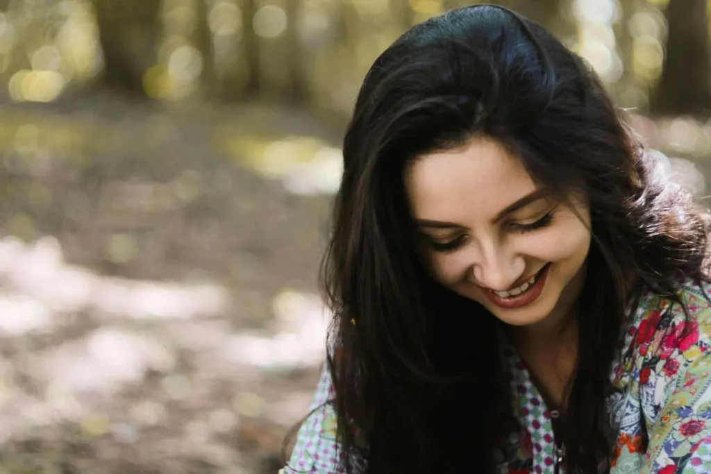 Mulher sorrindo com expressão serena e leve em ambiente natural ao ar livre transmitindo recuperação emocional e leveza