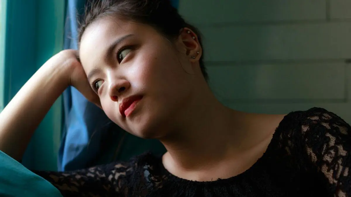 Mulher com olhar distante e expressão pensativa apoiada na mão representando a sensação de tristeza sem motivo aparente