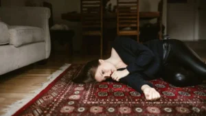 Mulher deitada no chão com expressão de cansaço e esgotamento emocional representando os sinais de burnout