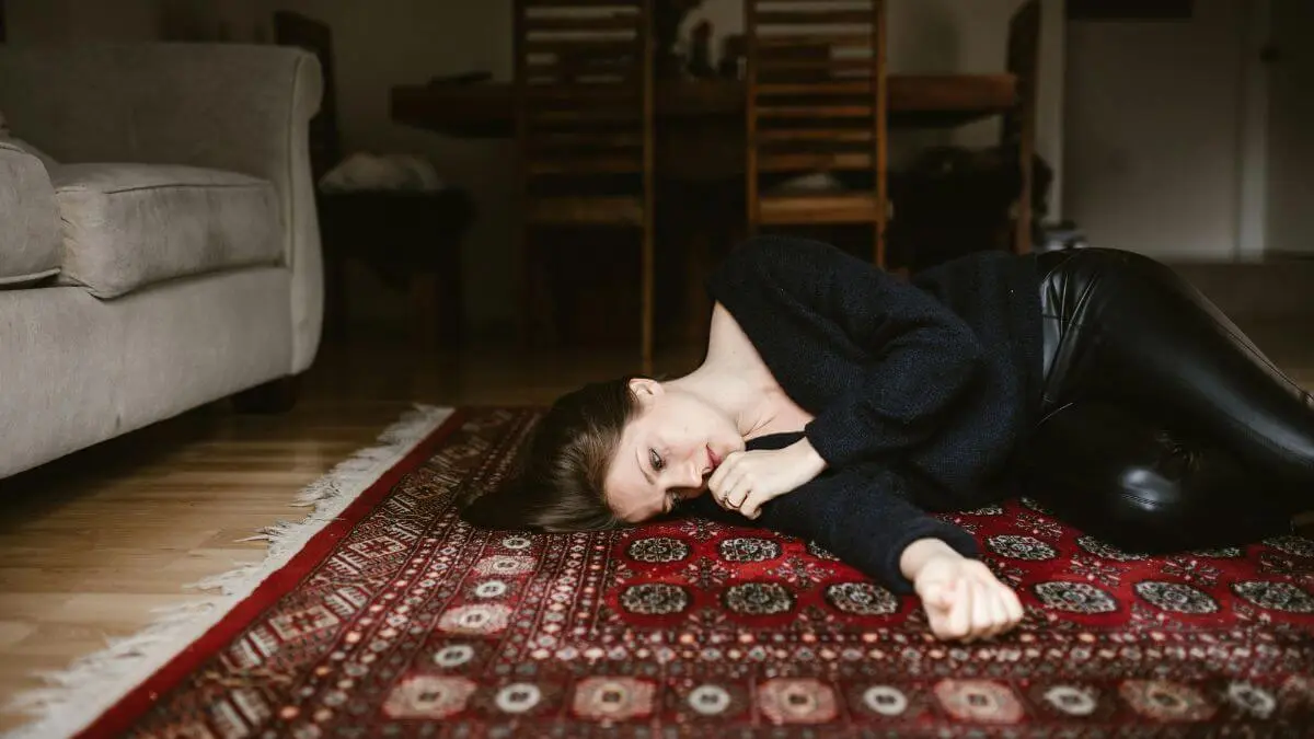 Mulher deitada no chão com expressão de cansaço e esgotamento emocional representando os sinais de burnout