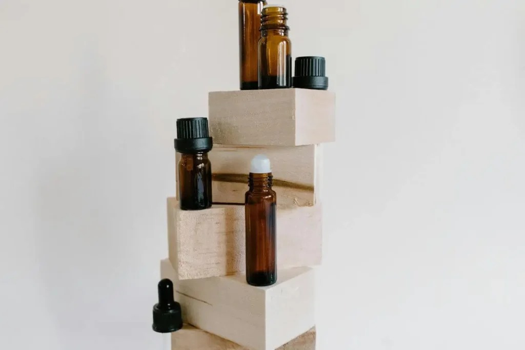  frascos de óleos essenciais âmbar com flores de lavanda seca sobre superfície de madeira