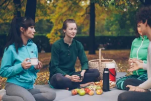 Grupo de mulheres sentadas ao ar livre conversando em clima acolhedor, transmitindo amizade, pertencimento e apoio emocional.