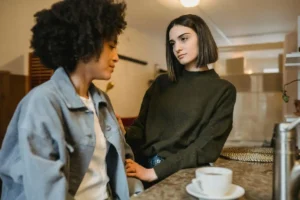Duas mulheres conversando em ambiente aconchegante, com expressão de escuta e apoio emocional.
