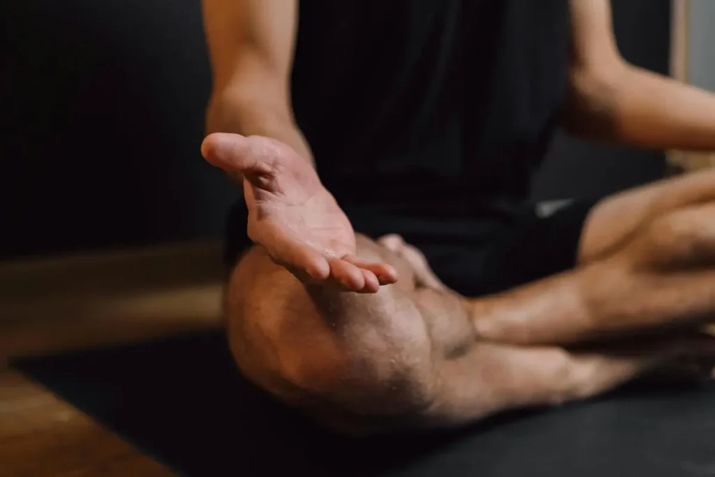 Mãos abertas com as palmas para cima sobre os joelhos, em postura relaxada de presença e calma após um momento de tensão emocional.