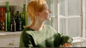 Mulher em momento de reflexão consciente perto da janela, com expressão serena e luz natural suave